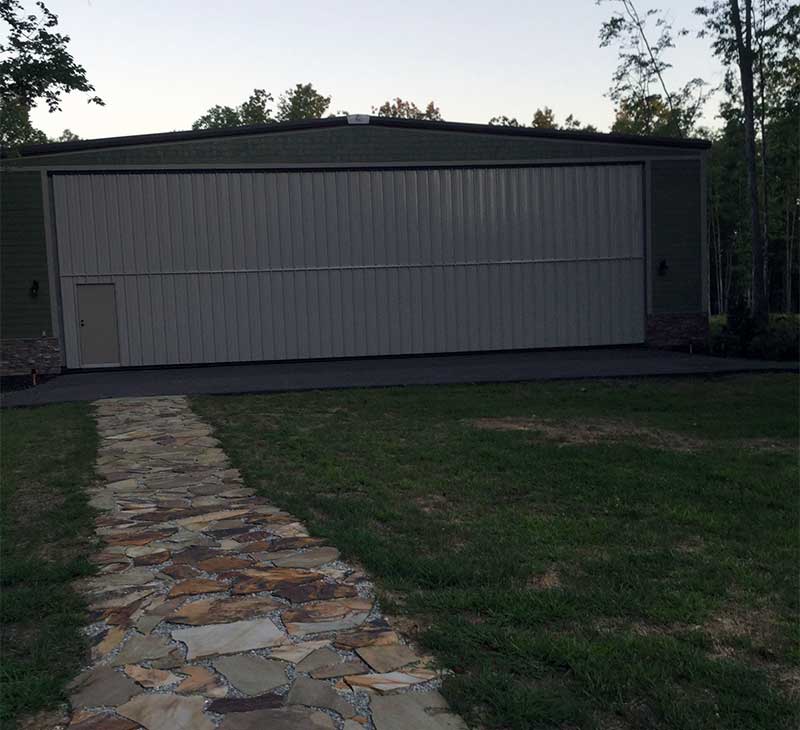 A stone paved walkway leads from the back of the Rogers home to his hangar.